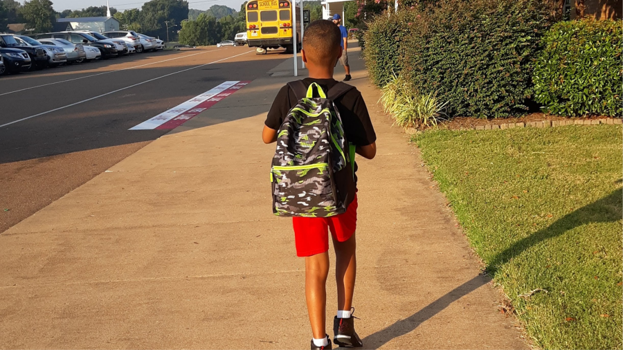 Young Boy Walking Down Sidewalk To School